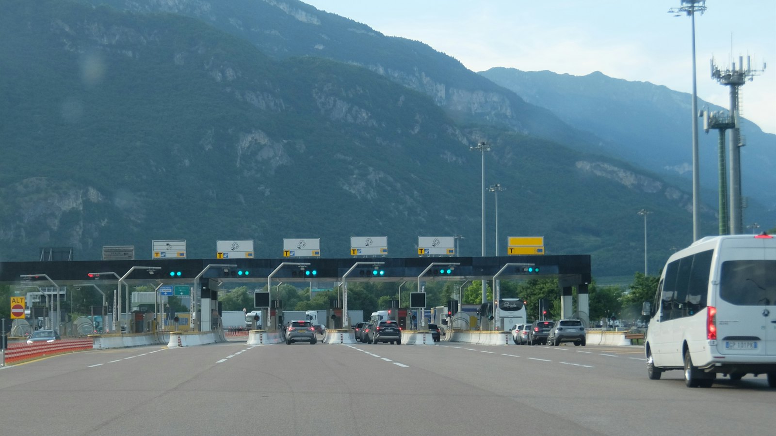 Cars approaching a multi-lane toll plaza with mountains behind