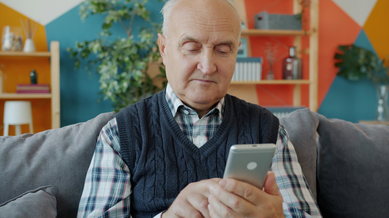 An older man on a sofa looking at his smartphone