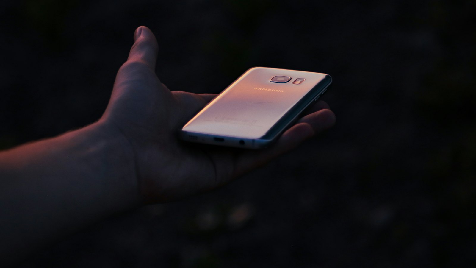 A phone glowing in an open hand in the dark