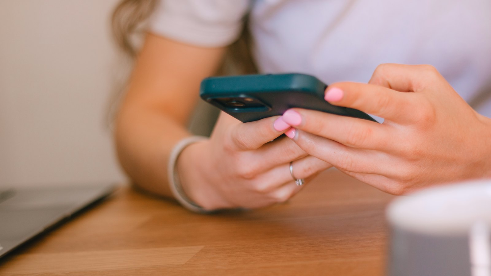 Hands holding a smartphone at a table