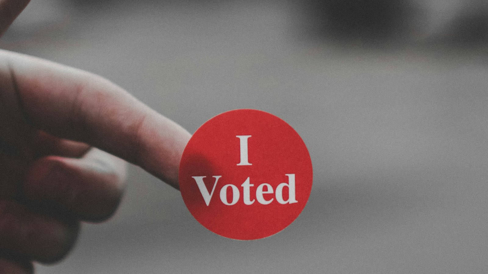 A hand holding an I Voted sticker