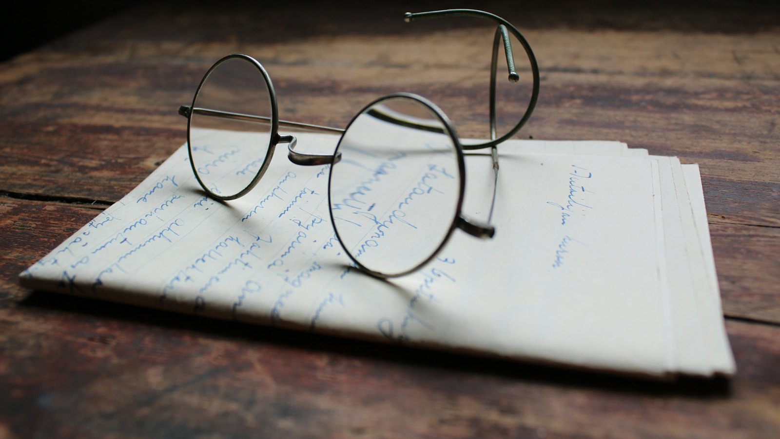 A pair of round glasses resting on a handwritten letter