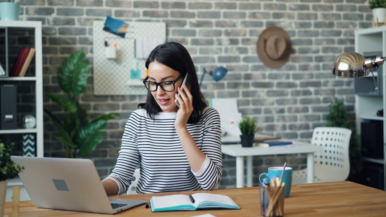 A woman on a phone call while working at her laptop