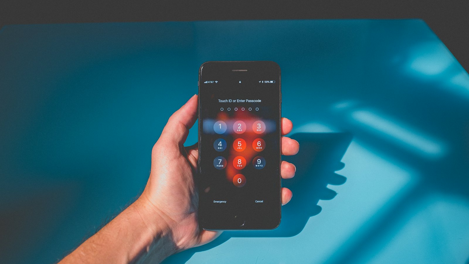 A hand holding a phone showing a passcode screen
