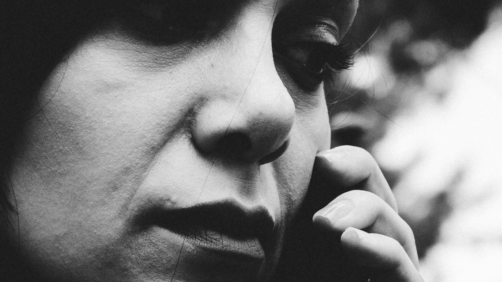 A black and white close-up of a woman on a phone call