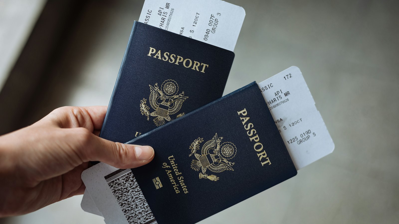 A hand holding two passports with boarding passes tucked inside