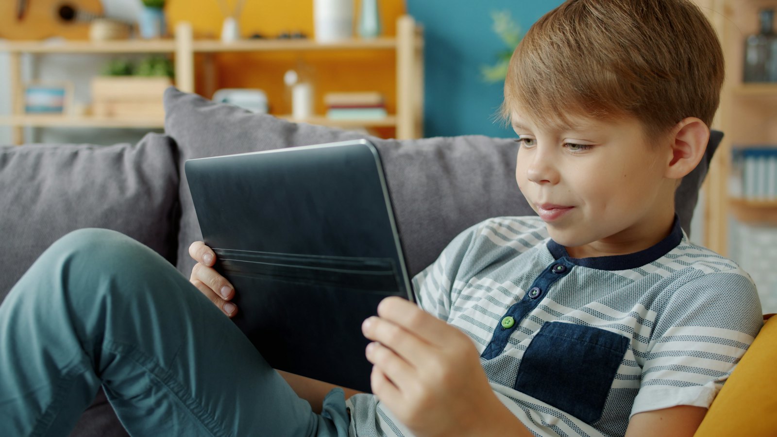 A boy using a tablet on a sofa