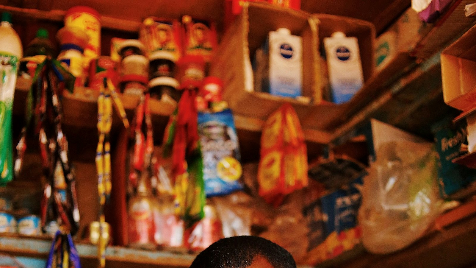 A shopkeeper standing among goods in a small shop