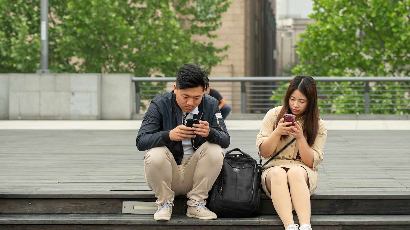 Two people using their phones on outdoor steps