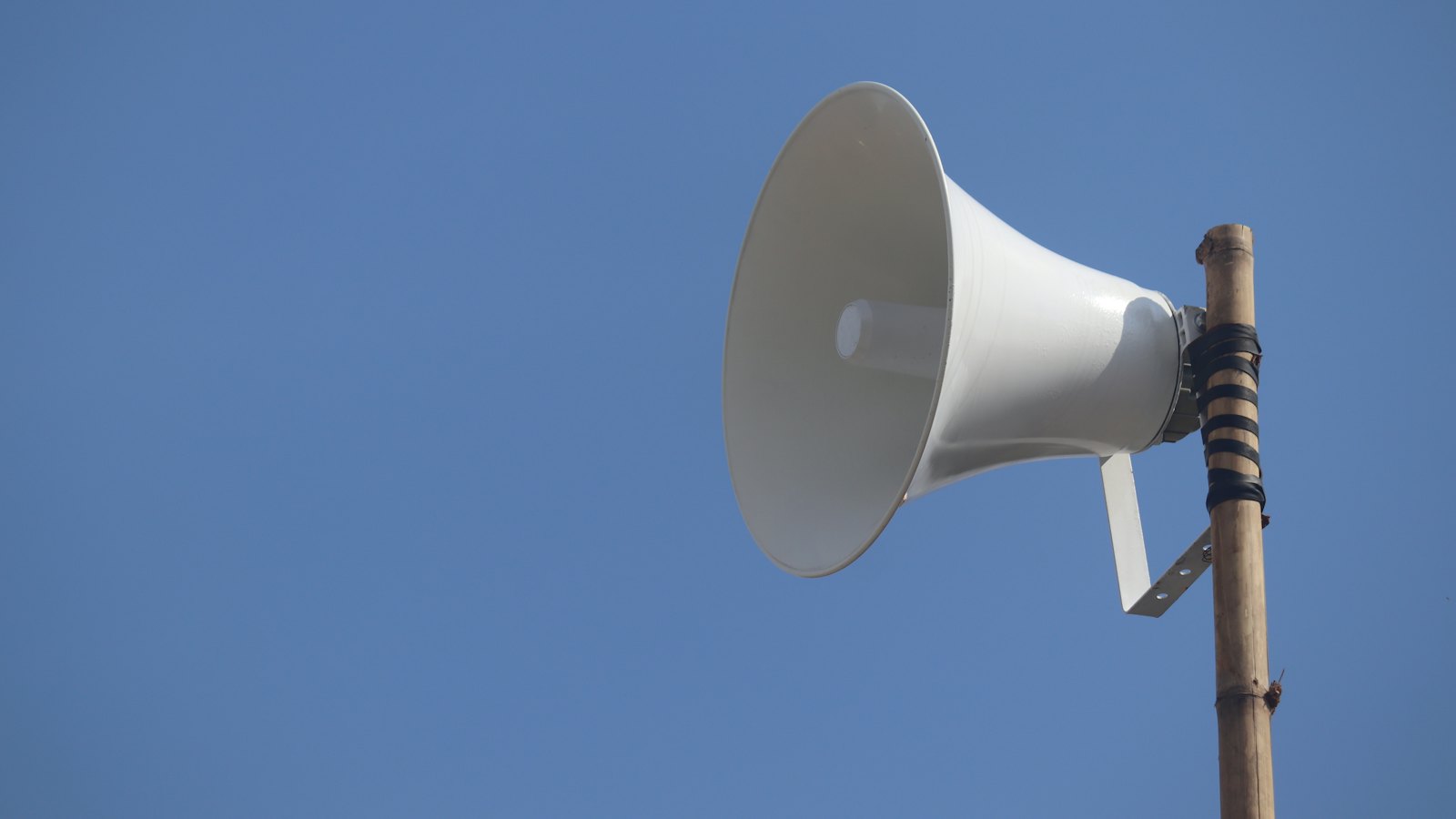 A loudspeaker on a pole against a blue sky