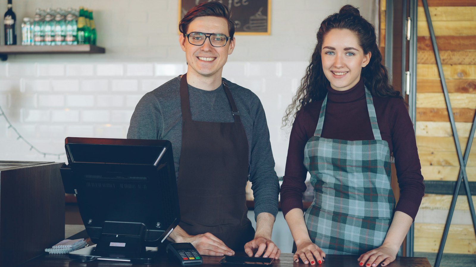 Two smiling cafe staff behind a counter