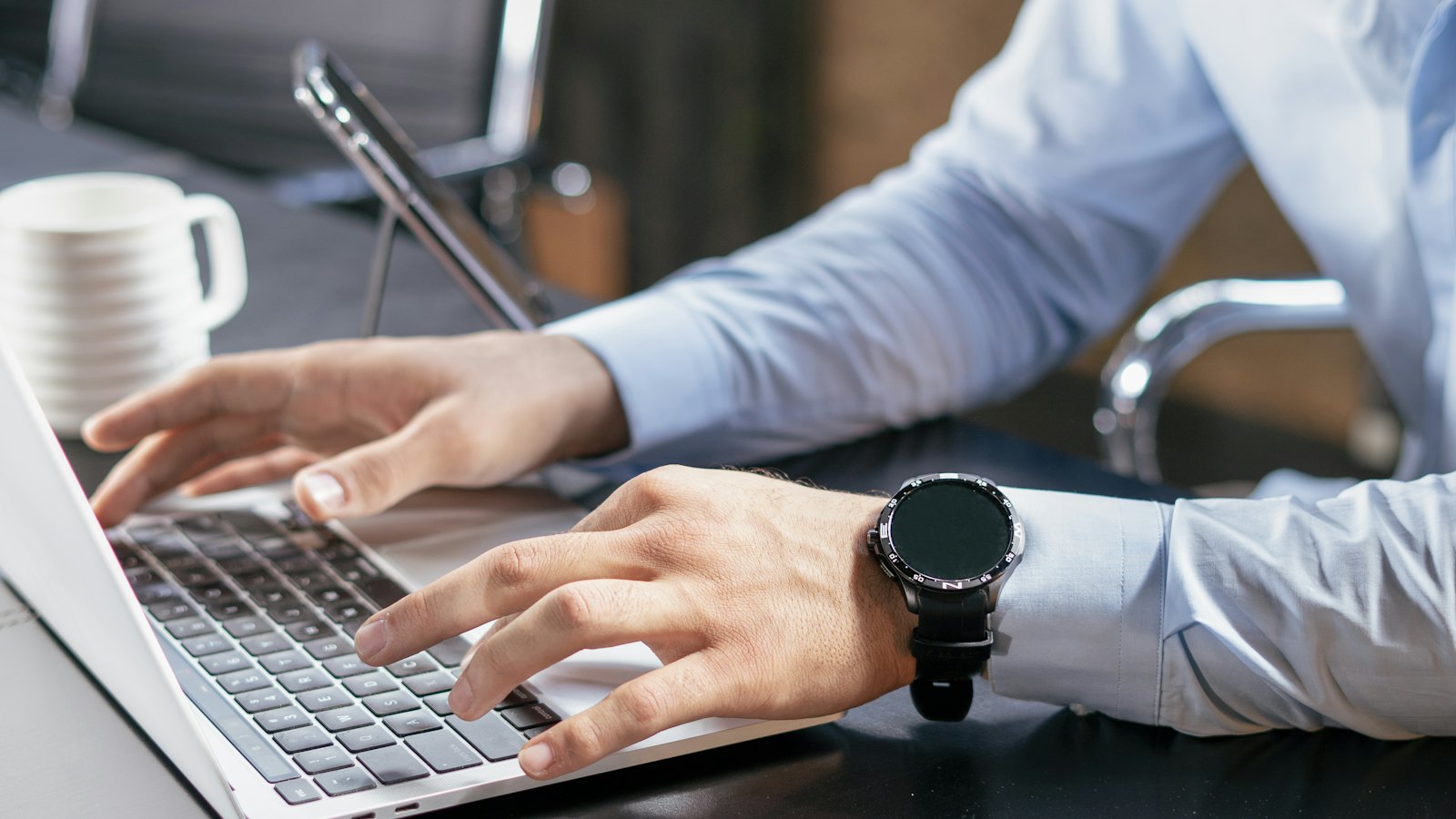 Hands typing on a laptop at a desk