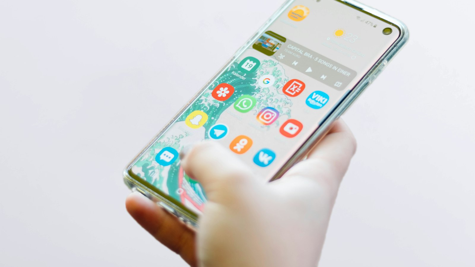 A hand holding a phone with app icons on the screen