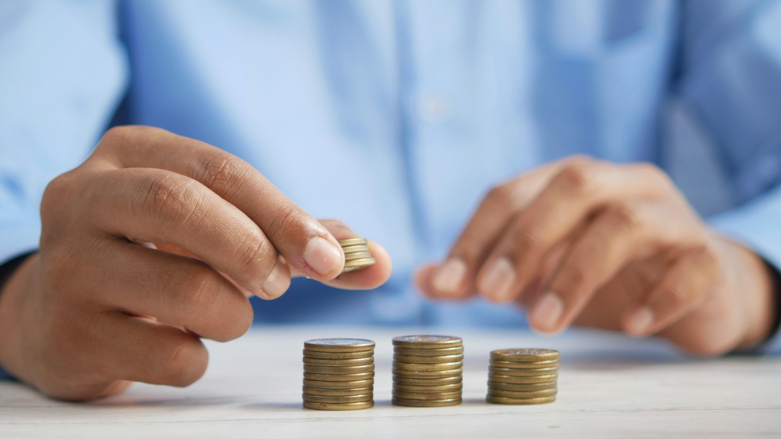A person stacking coins on a table