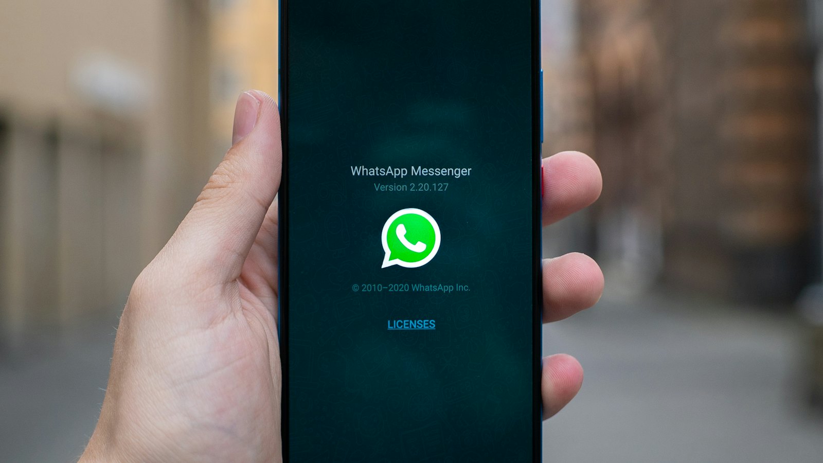 A hand holding a phone with the WhatsApp Messenger screen open