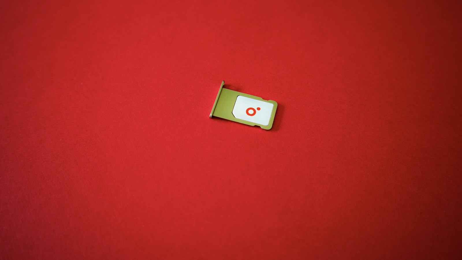 A SIM card in its tray on a red surface