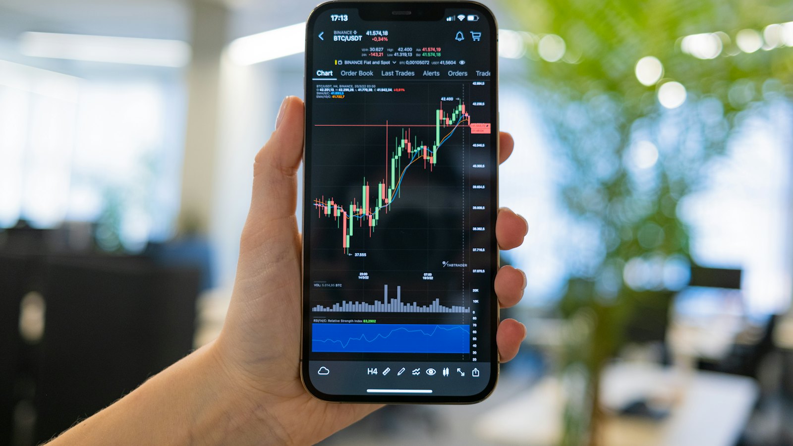 A hand holding a phone showing a trading chart