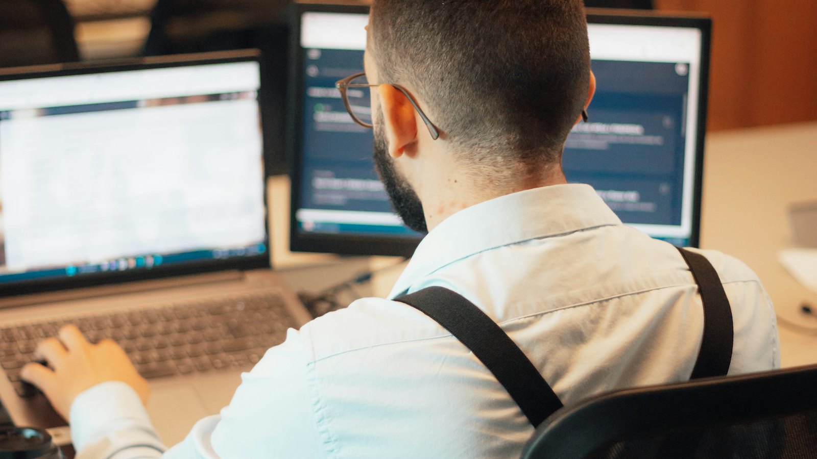 A man working at a desk with two screens