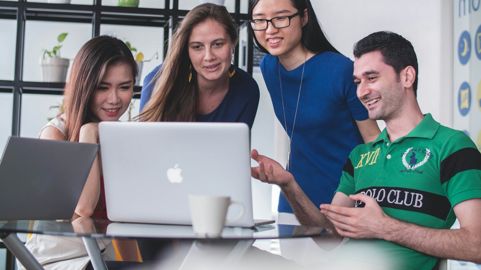 Colleagues gathered around a laptop in an office